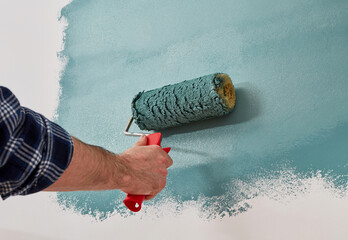 Male hand painting wall with paint roller