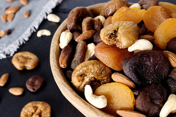 Wooden rustic bowl with variety of dry fruits and nuts healthy snacks.
