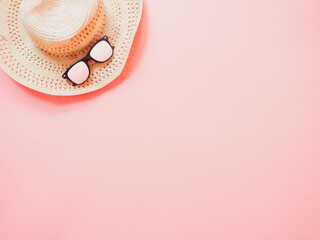 summer accessories concept from sunglasses and straw hat on pastel red background.