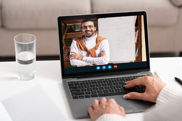 Fototapeta na wymiar Unrecognizable woman having online call with smiling middle-eastern teacher