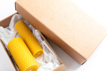 Fototapeta na wymiar Yellow candles made of bees wax in craft packaging for gift on white background