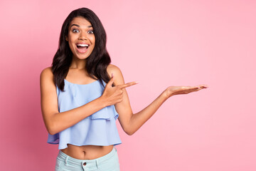 Photo of impressed brunette lady hold point empty space wear blue top isolated on pink color...