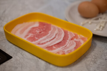Thinly sliced of raw pork on yellow tray is popular local food in asian countries.