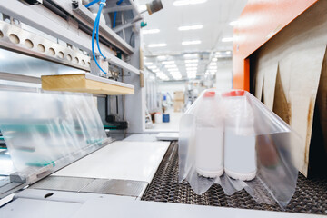 Fototapeta na wymiar Dairy industry, thermal packer of milk bottles in plastic bags sets