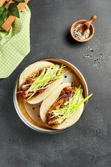 Bao bun with hoisin chicken. Bamboo steamer on dark slate table. Chinese, asian, authentic food concept