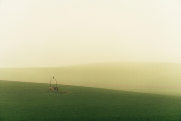 Naklejka na ściany i meble Stock photo of rural landscape against foggy sky. Well in a green meadow.