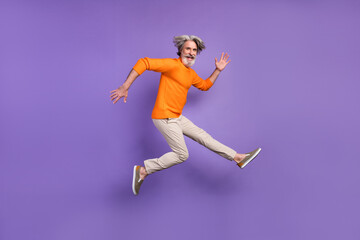 Full body profile side photo of aged man have fun jump happy positive smile isolated over purple...