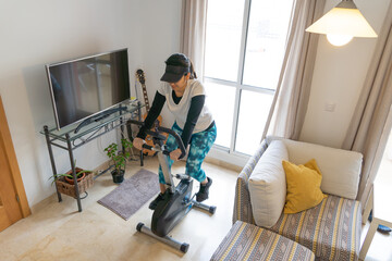 Stock photo of adult woman using stationary bike at home.