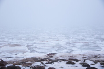 foggy beach with rocks in snow and ice at winter