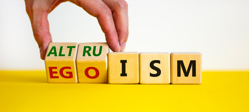 Altruism or egoism symbol. Businessman turns wooden cubes and changes the word 'egoism' to 'altruism'. Beautiful white background, copy space. Business, psychological and altruism or egoism concept.