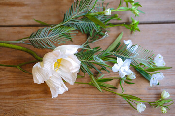 Spring white flowers with green leaves on a wooden table