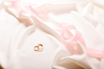 Obraz na płótnie Canvas wedding rings on a white dress with pink tape
