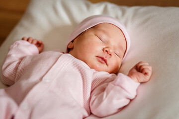 newborn baby of less than a week in a pink jumpsuit sleeps on a white plaid. Cute Little Close