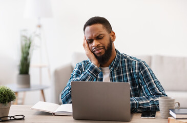 Unhappy African Man At Laptop Working Online Sitting In Office