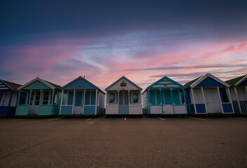 A row of colourful beach huts at dawn on the coast of Suffolk, UK