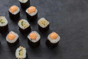 Rolls on a stone platter. Roll with cucumber, cheese sprinkled with sesame seeds. view from 45 degrees