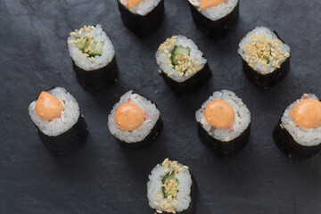 Rolls on a stone platter. Roll with cucumber, cheese sprinkled with sesame seeds