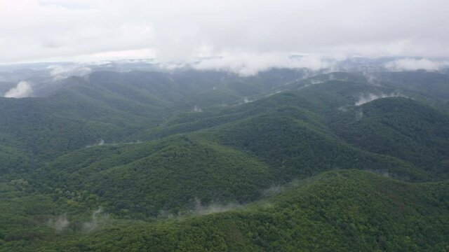 Drone flight over green mountain slopes with creeping spring mists above them, Strandzha Mountain, Bulgaria