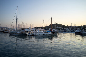 Fototapeta na wymiar Landscape with boats in marina bay. Beautiful aegean sea with calm water, boats and yachts. Sunset sky in the background. Bodrum, Turkey.