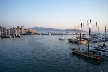 Fototapeta na wymiar Bodrum castle, mountains and sailing boats, Turkey. Harbor with boats in Aegean sea.