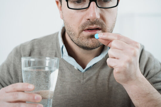 Man Taking Aspirin Pill On White Background