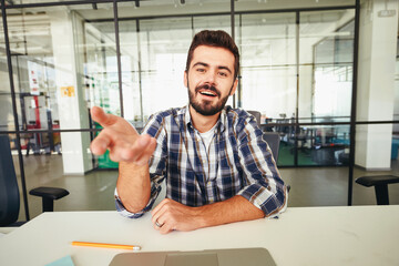 Active young man extending hand towards laptop screen