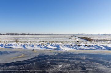 frozen and snowy Dutch landscape with clear blue sky