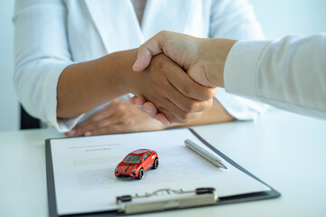Insurance agent joins hands with the insured after proposing the concept of car insurance. And...