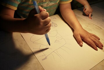child draws with ball pen on paper