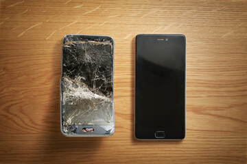 Mobile smartphone with broken screen on wooden background. Repairs concept.