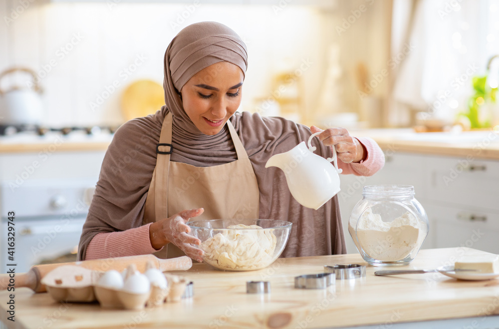 Wall mural Beautiful Muslim Woman In Hijab Baking In Kitchen, Preparing Dough For Cookies