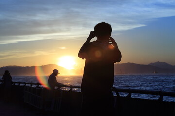 photographers under the sunset take picture for city skyline in victoria harbour, hong kong china
