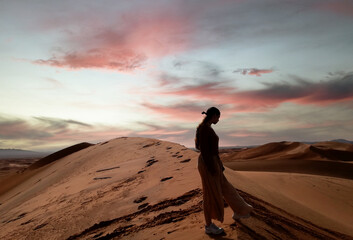 Woman silhouette on the highest dune in the sahara desert at sunset