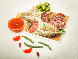 Traditional salami with rosemary and olives on wooden board