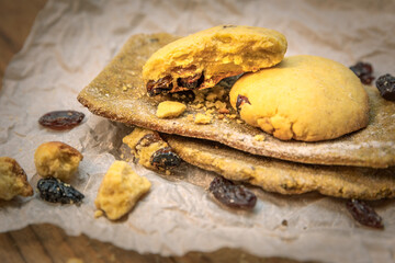 Close-up pile of homemade fresh tortillas and cookies with raisins on parchment paper on table
