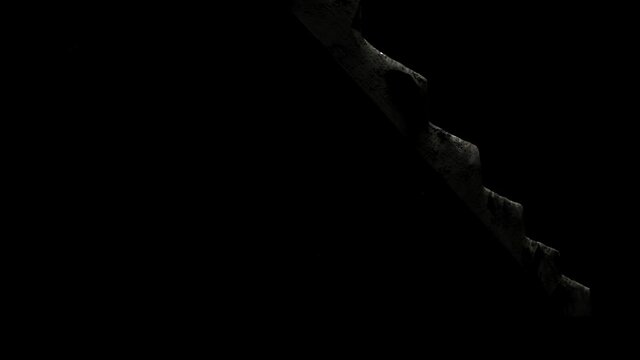 The camera scans the monstrous saw made of stone from bottom to top against a black background. Horror movie.