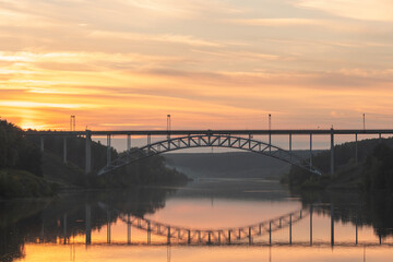 Obraz premium landscape of a railway bridge over the river during sunset