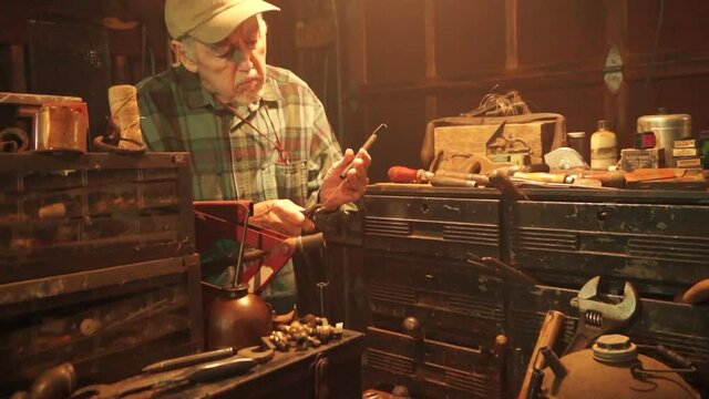 Camera dollies in over workbench to old man working.