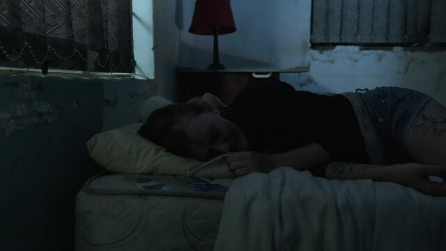 Dolly push in of woman crying in bed