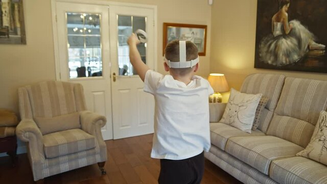 Boy playing and interacting with futuristic virtual reality game and goggles at home