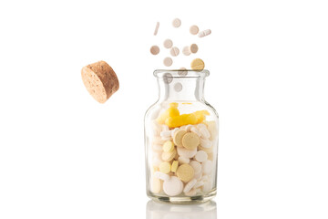 various pills fly out of a glass jar of pills isolated on a white background