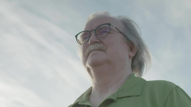 Close up of man with glasses looking out in the distance.