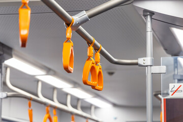 Orange triangular handles for standing passengers. Transport handrails for passenger safety