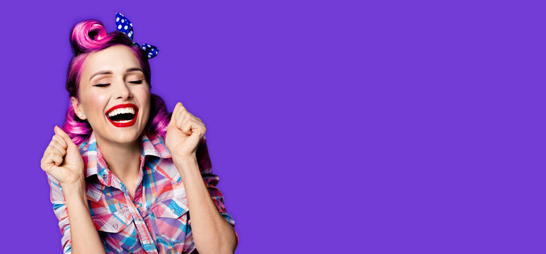 Unbelievable news! Excited surprised, very happy purple woman. Pin up girl with open mouth and closed eyes with raised hands. Retro and vintage concept. Violet color background. Wide composition image