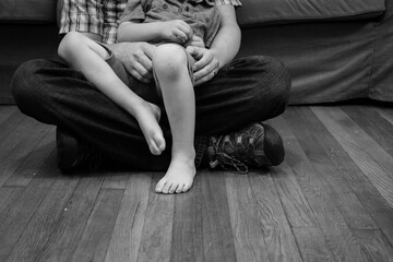 Father and son sitting on the floor; child in dad's lap