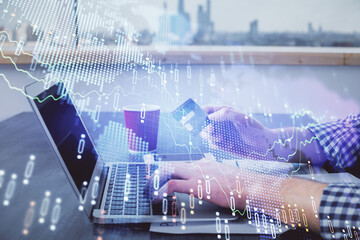 Double exposure of man hands holding a credit card and Forex graph drawing. Stock trading and digital fintech in Internet E-commerce concept.