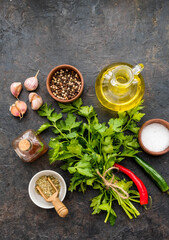 Prepared ingredients for chichimuri, Argentinean green steak sauce with fresh parsley, garlic, olive oil and oregano on a dark concrete background. Sauce recipes.