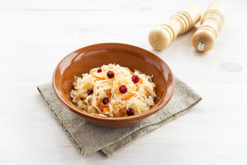 Sauerkraut with cranberries in a clay bowl. Russian traditional food.