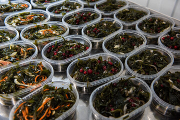 Different fish and chuka wakame laminaria seaweed salad in plastic bowles. Concept of healthy food production or delivery food