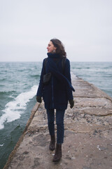 Beautiful woman walking on the beach with seagulls in winter time.